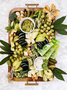 a platter filled with vegetables and dips on top of a marble countertop