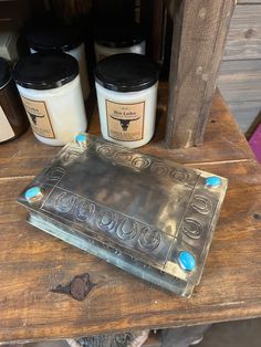 some jars are sitting on top of a wooden table next to an old metal plate