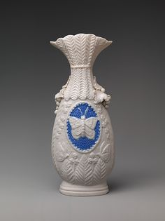 a white vase with a blue and white design on the bottom, sitting on a gray surface