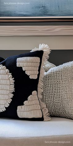 two black and white pillows sitting on top of a couch next to a framed painting