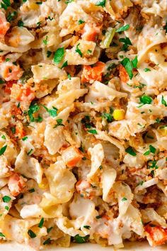 a dish with pasta, meat and vegetables is shown in a white casserole dish