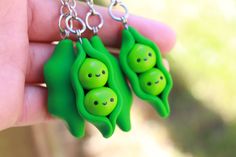 two peas hanging from a silver chain in the shape of people's heads, with faces drawn on them