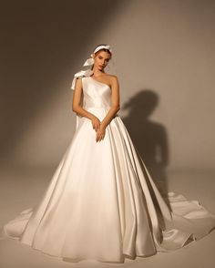 a woman in a white wedding dress posing for the camera with her hands on her hips