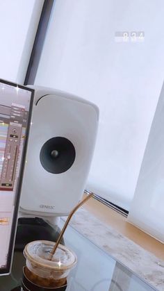 a computer monitor sitting on top of a desk next to a coffee cup and speakers