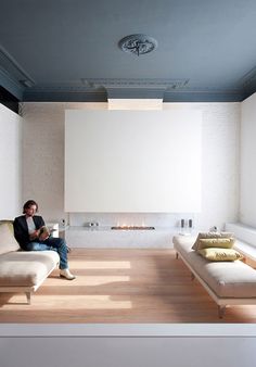 a man sitting on a couch in front of a fire place next to a fireplace