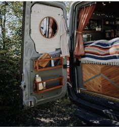 there is a bed in the back of a van with it's door open