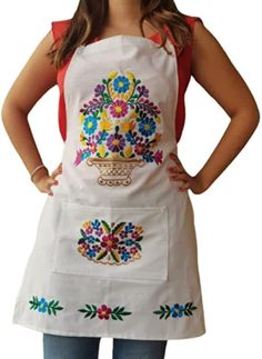 a woman wearing an apron with colorful flowers on the front and side, standing in front of a white background