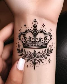 a woman's wrist tattoo with a crown on it