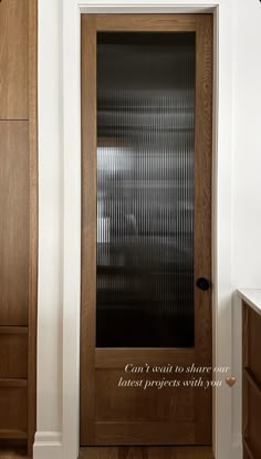 a wooden door with blinds on it in a white and brown room next to a cabinet