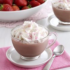 two glasses of hot chocolate with whipped cream and candy canes next to them on a table