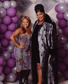 two women standing next to each other in front of balloons