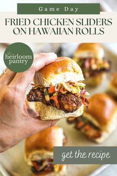 a hand holding a chicken slider on hawaiian rolls with the title game day fried chicken sliders on hawaiian rolls get the recipe