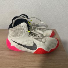 a pair of white and red sneakers on top of a wooden table