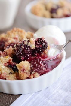 a bowl filled with ice cream and berry crumbles on top of a table