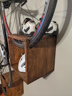 a bicycle tire is mounted to a wooden box with two pairs of shoes in it