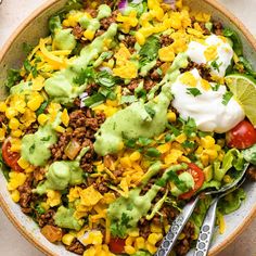 a bowl filled with taco salad topped with sour cream and avocado dressing