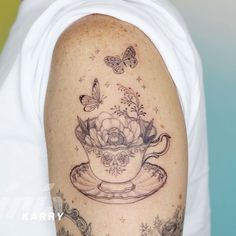 a woman with a tattoo on her arm has a teacup and butterflies in it