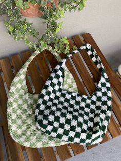 a green and white purse sitting on top of a wooden table next to a potted plant