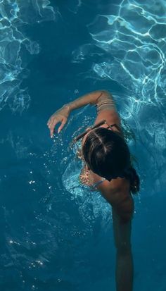 a woman swimming in a pool with her hand on the water