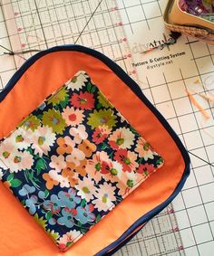 an orange and blue bag sitting on top of a cutting board next to some scissors