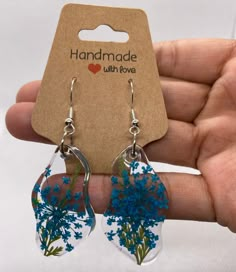 a pair of handmade earrings with blue flowers in the center and clear tears hanging from them