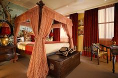 a canopy bed in a bedroom with curtains on the windows