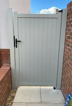 a grey wooden gate in front of a brick wall