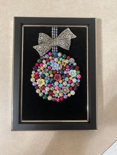 a framed picture with beads in the shape of a christmas ornament and bows