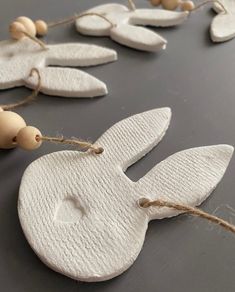 some white wooden ornaments are hanging on a string with wood beads and twine around them