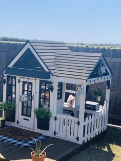 a white and blue house with potted plants on the deck in front of it