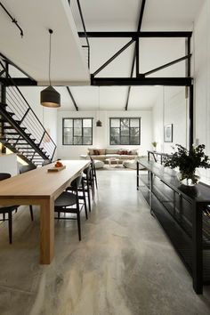 an open concept living room and dining area in a house with white walls, wood flooring and black iron railings