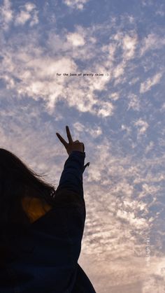 a person with their hand up in the air and writing on the sky behind them