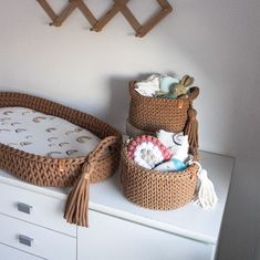 two wicker baskets are sitting on top of a dresser next to a baby's crib