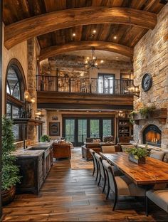 a large open floor plan living room and dining area with stone walls, wood floors and vaulted ceiling