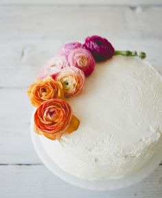 a white cake topped with flowers on top of a wooden table