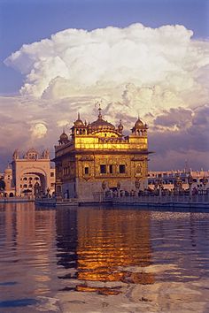 the golden building is reflected in the water near other white buildings and blue sky with clouds