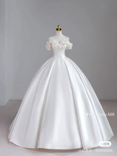 a white wedding dress on a mannequin with an off the shoulder neckline