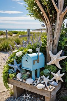 a blue mailbox sitting on top of a wooden box filled with plants and seashells