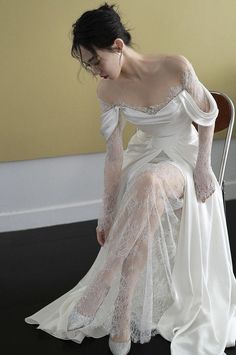 a woman sitting on a chair in a white dress