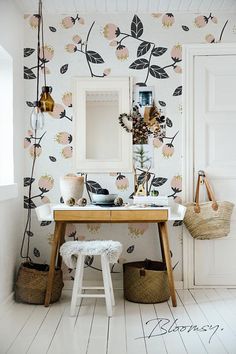 a room with white floors and flowers on the wall, along with a wooden table