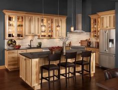 a large kitchen with wooden cabinets and black counter tops, along with bar stools