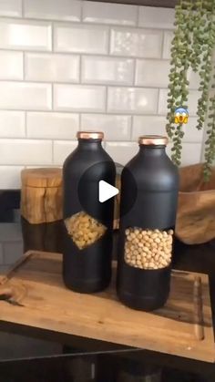 two black bottles filled with nuts on top of a wooden table