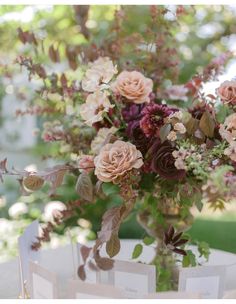 a vase filled with lots of flowers on top of a white tablecloth covered table