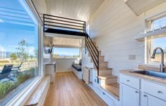 the interior of a tiny home with stairs leading up to the kitchen and living room