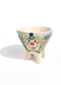 a ceramic bowl with a clown face painted on the side and flowers in the bottom