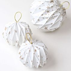 two white origami ornaments with gold stars on them