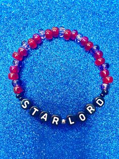 a red and blue beaded bracelet with the word star lord written in black letters