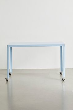 a blue table sitting on top of a cement floor next to a white wall in an empty room