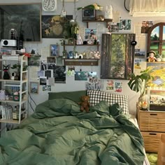 there is a bed with green sheets and pictures on the wall above it in this bedroom