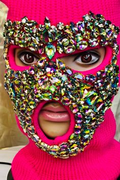 a person wearing a pink mask with lots of jewels on it's face and mouth